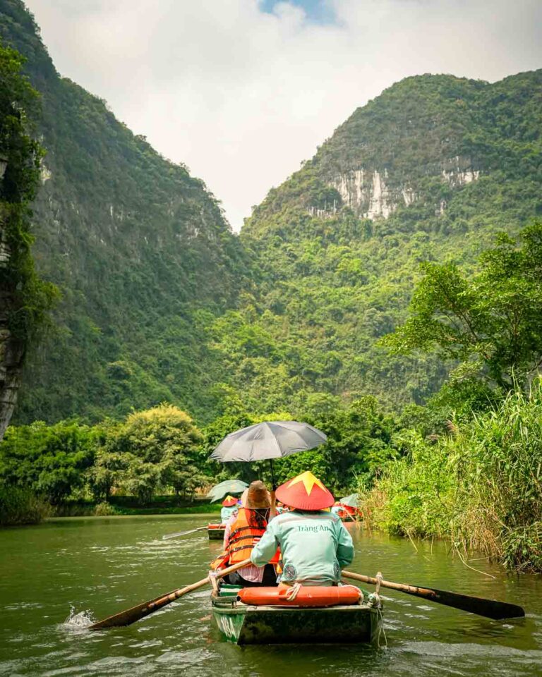 A boat paddling through limestone mountains