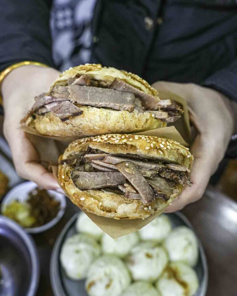 Hands holding two meat-stuffed buns