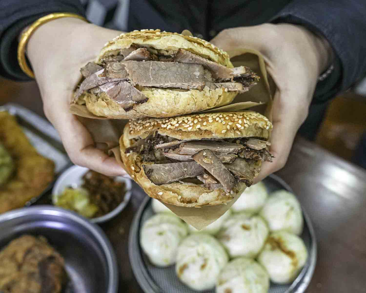 Eater holding two giant meat-stuffed flatbreads