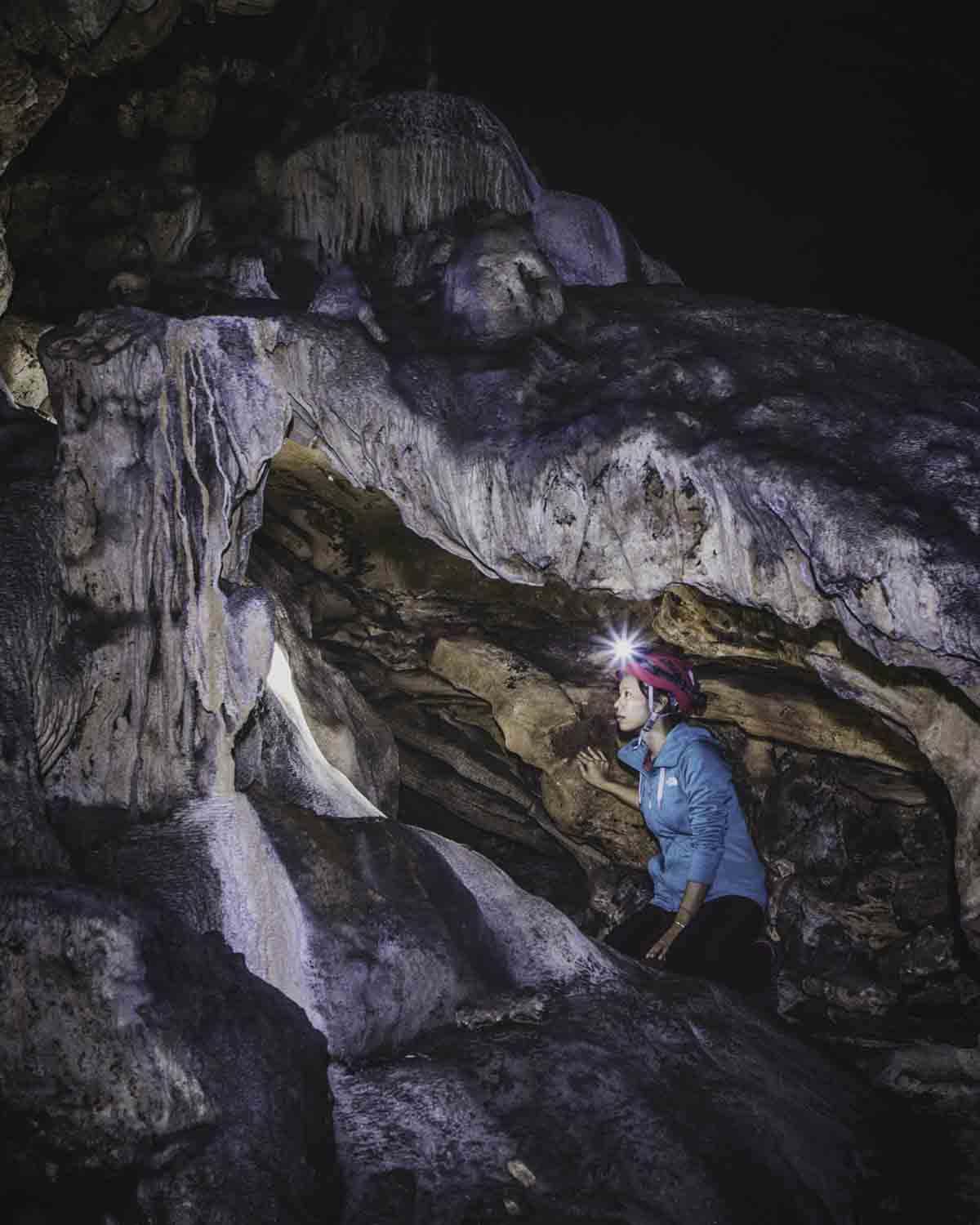 Person walking through cave with headlight
